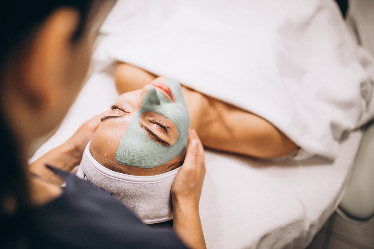 Cosmetóloga aplicando tratamiento facial a una clienta en salón de belleza