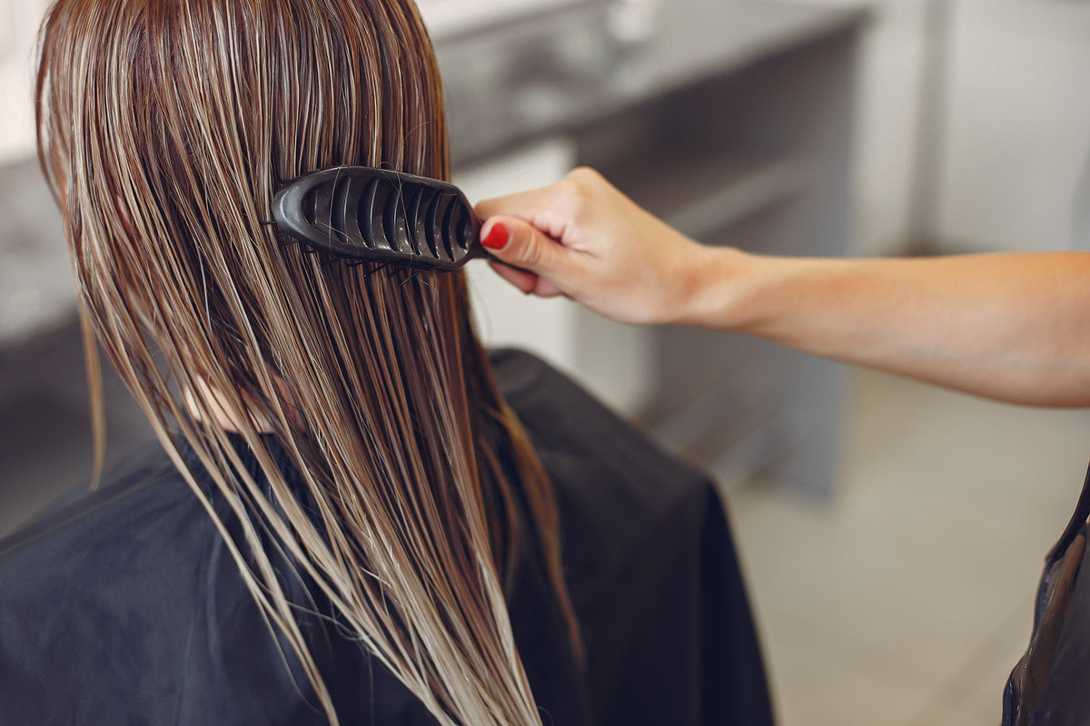Estilista secando el cabello de una clienta en un salón de belleza